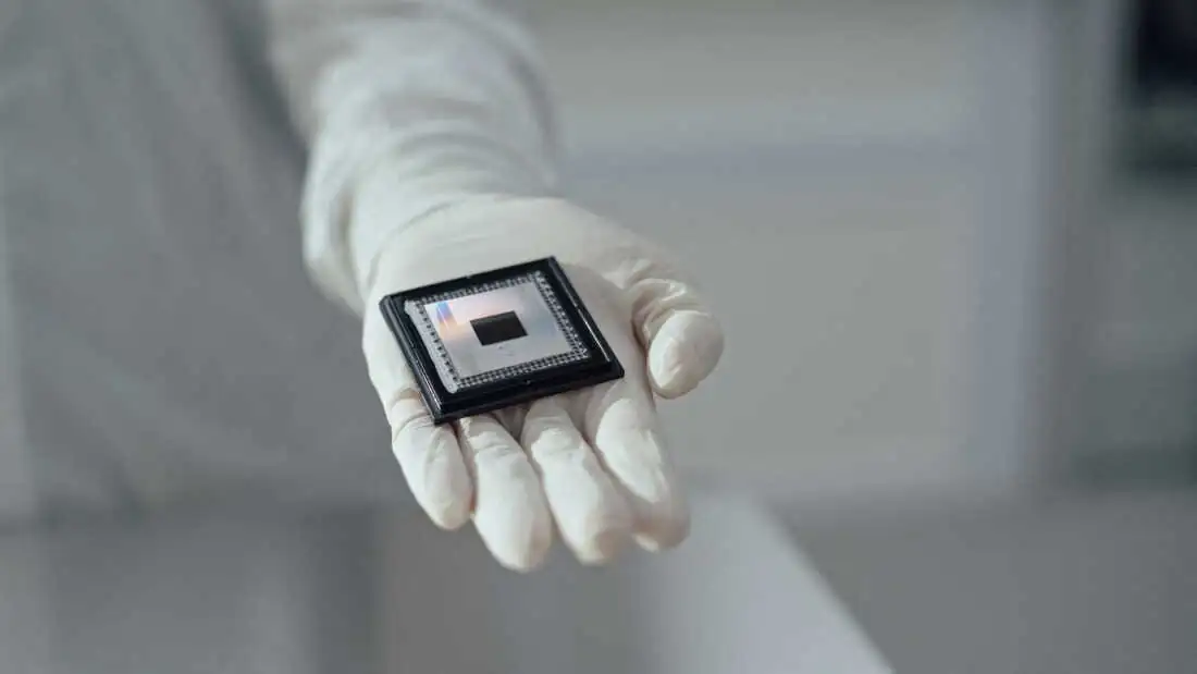 Engineer in a cleanroom glove holding a semiconductor microchip
